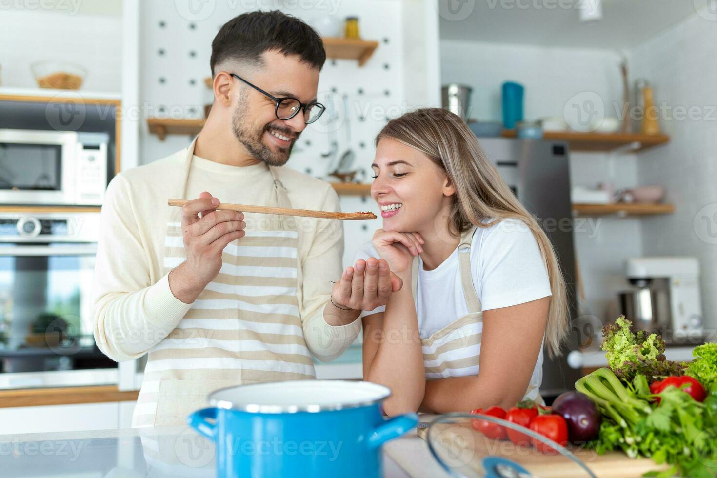 Portrait of happy young couple cooking together in the kitchen at home. romantic Attractive young woman and handsome man are enjoying spending time together while standing on light modern kitchen. photo