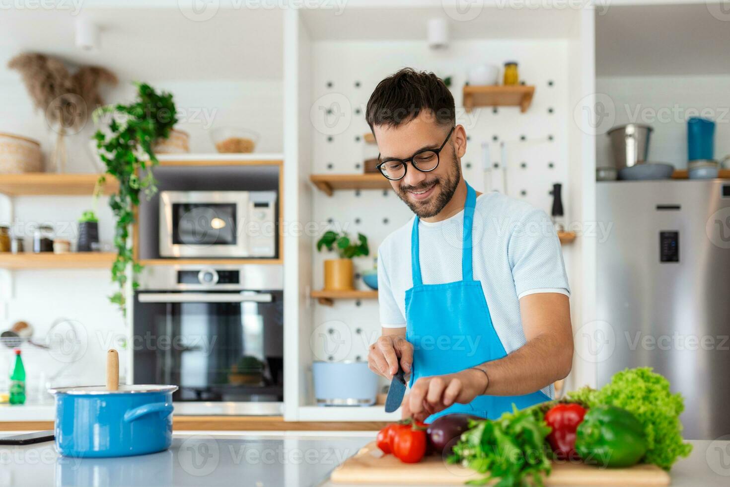 Handsome young man man stand at modern kitchen chop vegetables prepare fresh vegetable salad for dinner or lunch, young male cooking at home make breakfast follow healthy diet, vegetarian concept photo