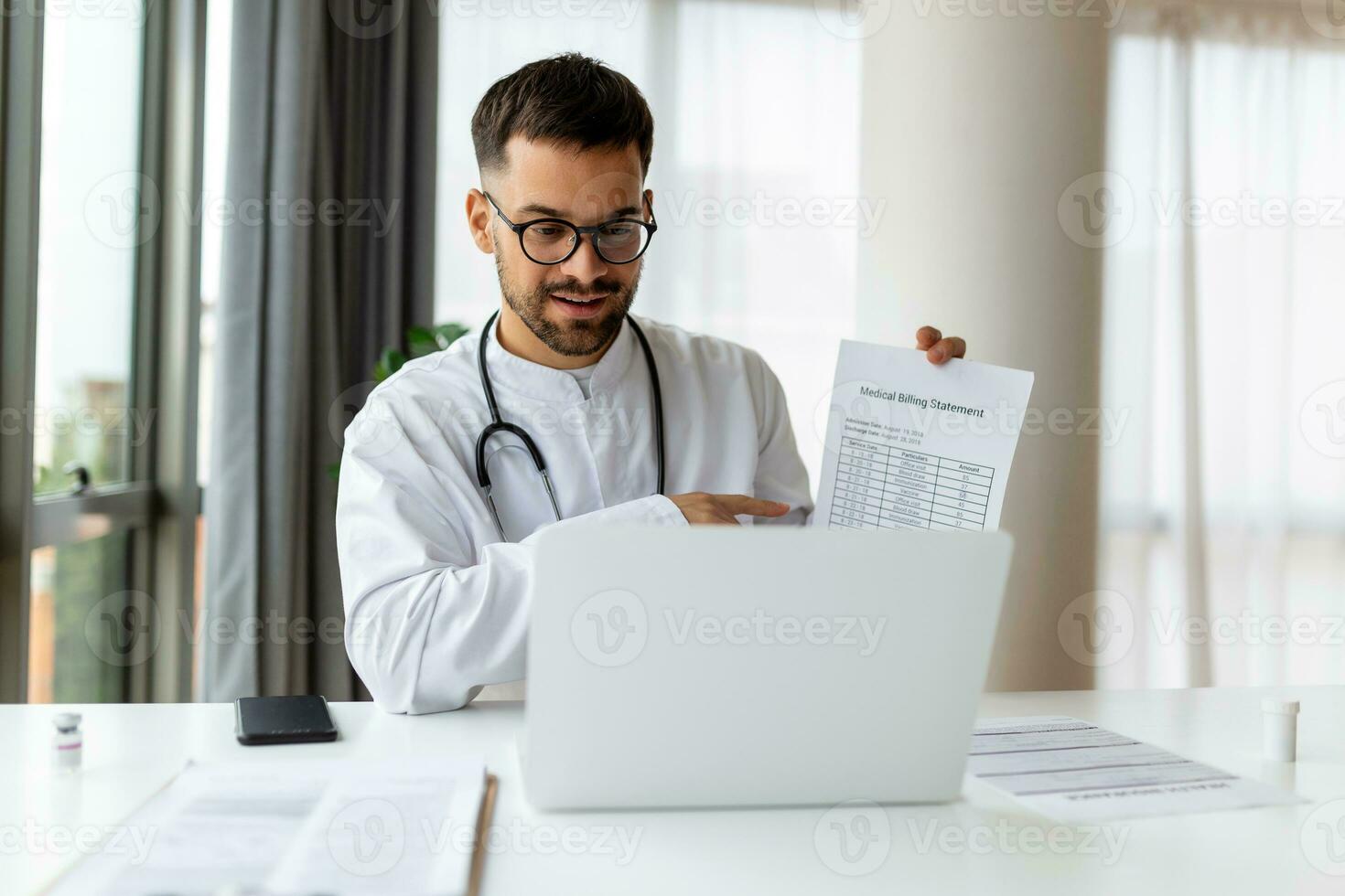 Young male doctor consulting patient online via conference video call service using laptop computer in medical office. Healthcare technology and pandemic quarantine webmedicine. photo