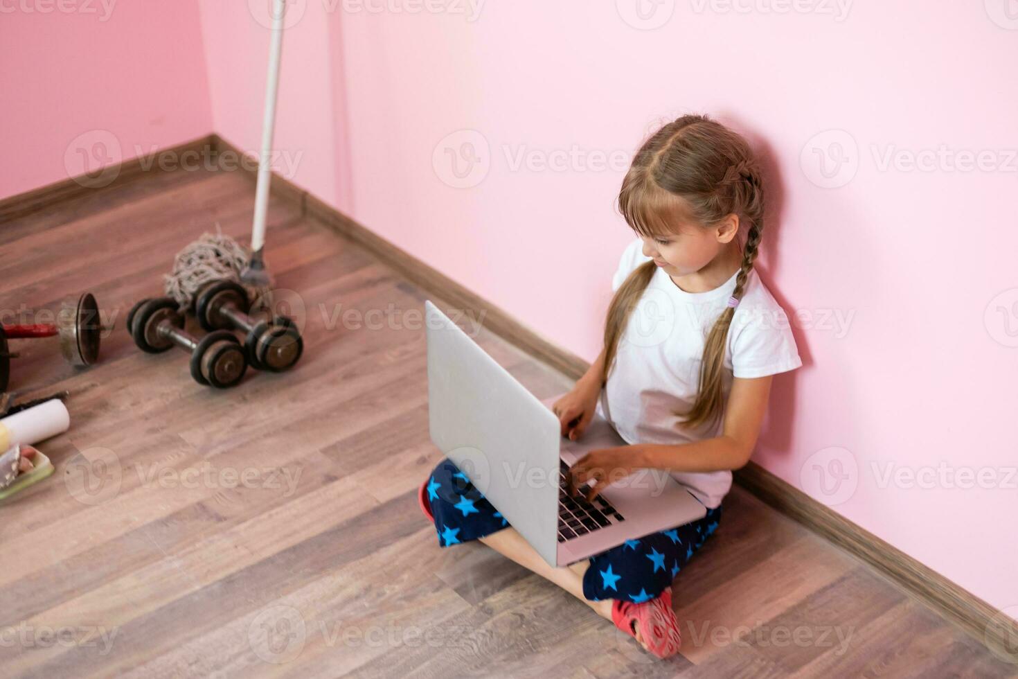 Remote lessons. The child smiles happily and gets knowledge remotely. Little girl study online learning from home with laptop. Online school. photo