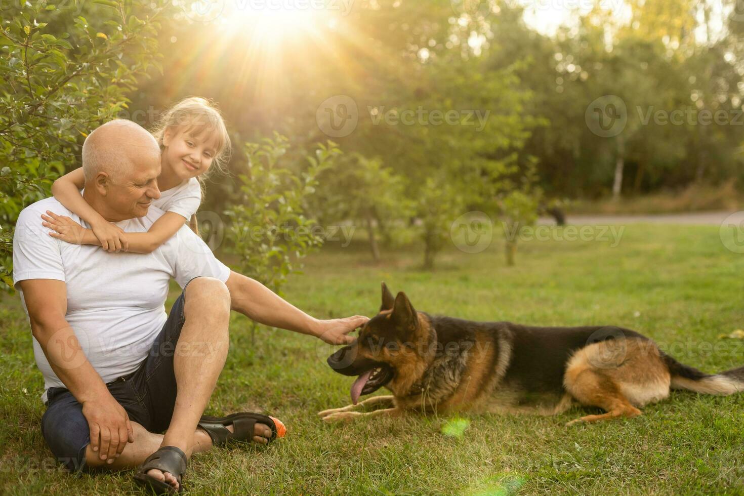 Grandfather with granddaughter and a dog in the garden photo