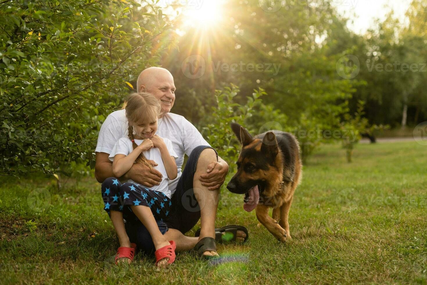 Grandfather with granddaughter and a dog in the garden photo