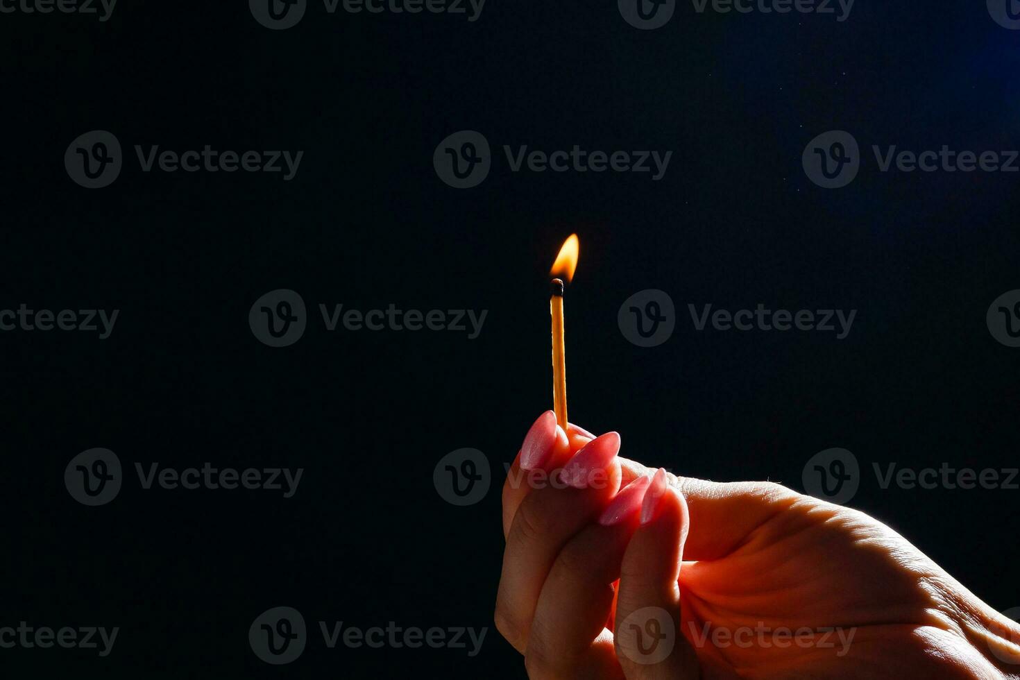 Hand holding burning match stick on black background photo