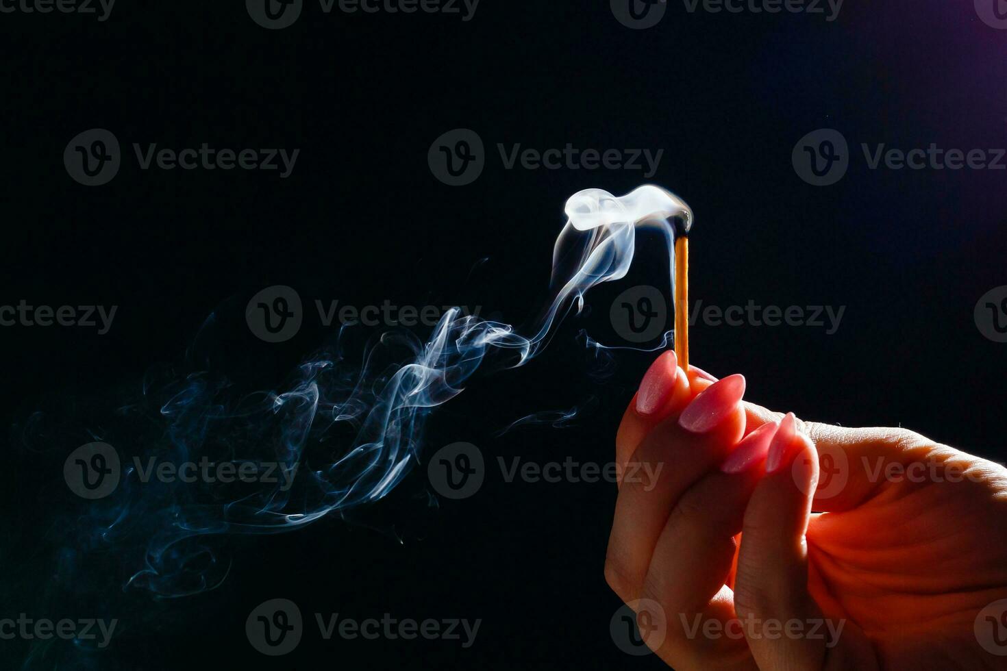 Hand holding match stick on black background photo