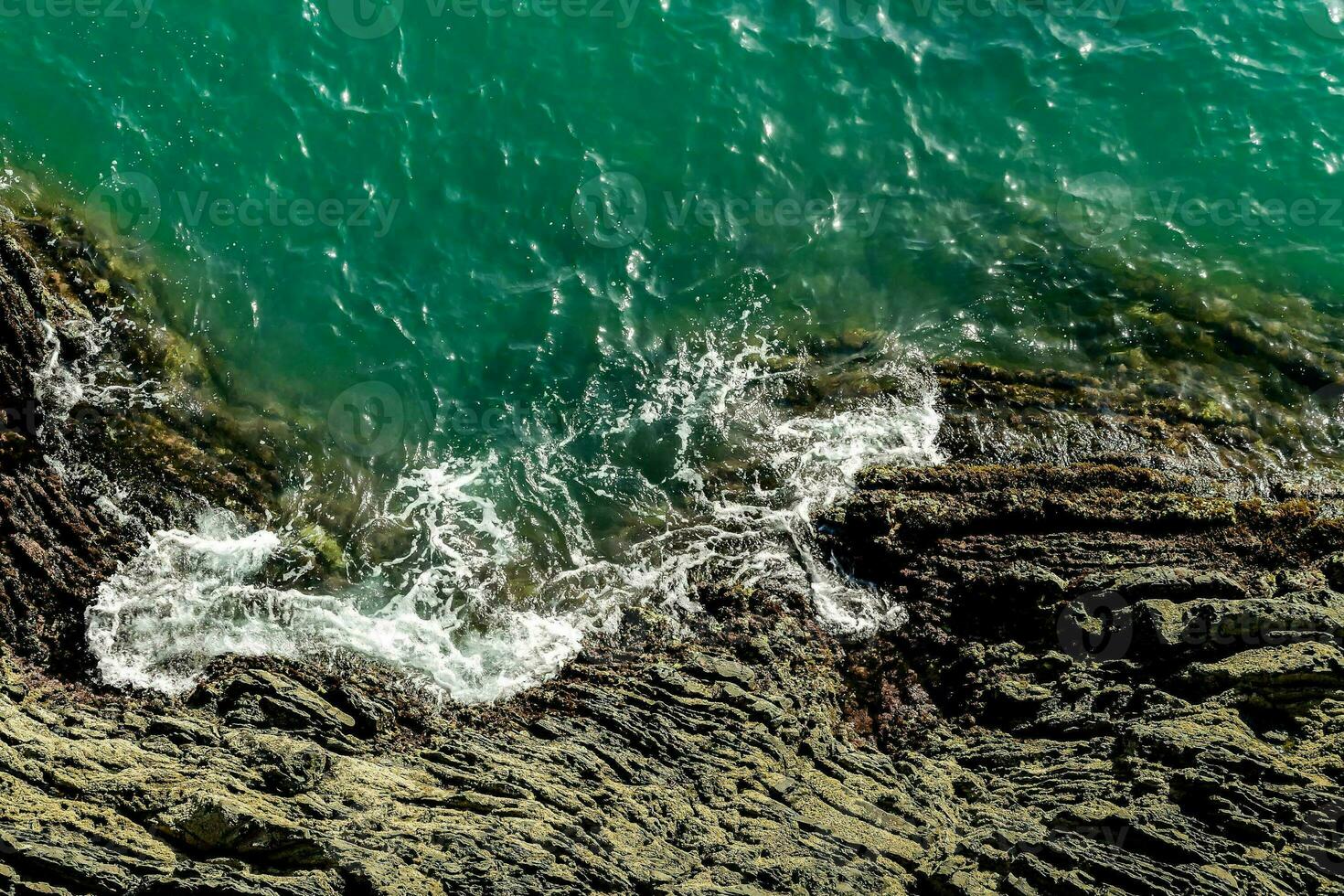an aerial view of the ocean and rocks photo