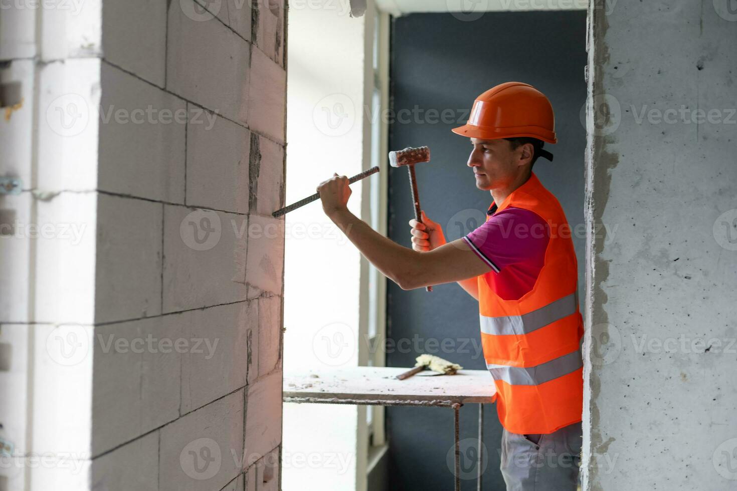 Young worker holding a hammer and a pointed chisel photo