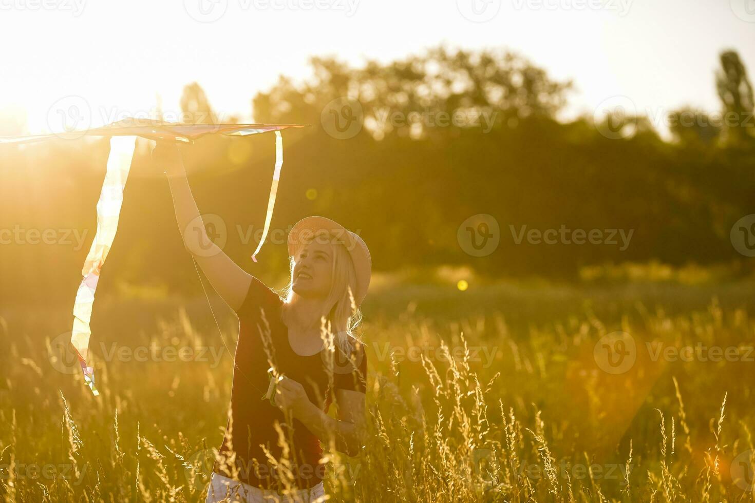 Portrait of a young and carefree woman launching kite on the greenfield. Concept of active lifestyle in nature photo