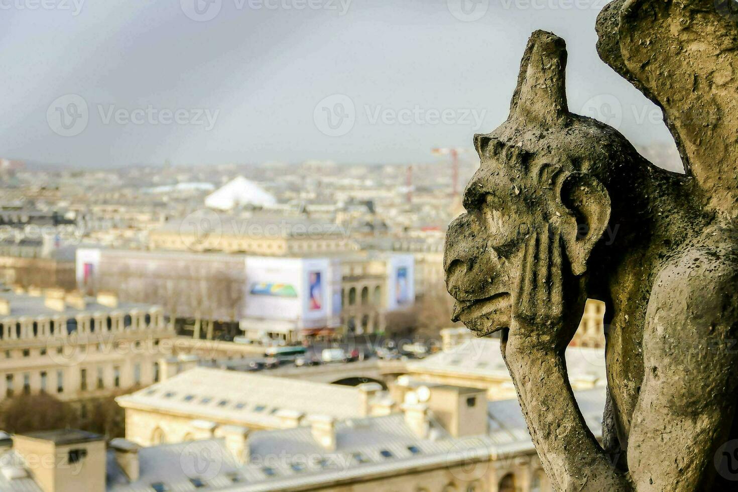 a gargoyle statue on the roof of a building overlooking a city photo