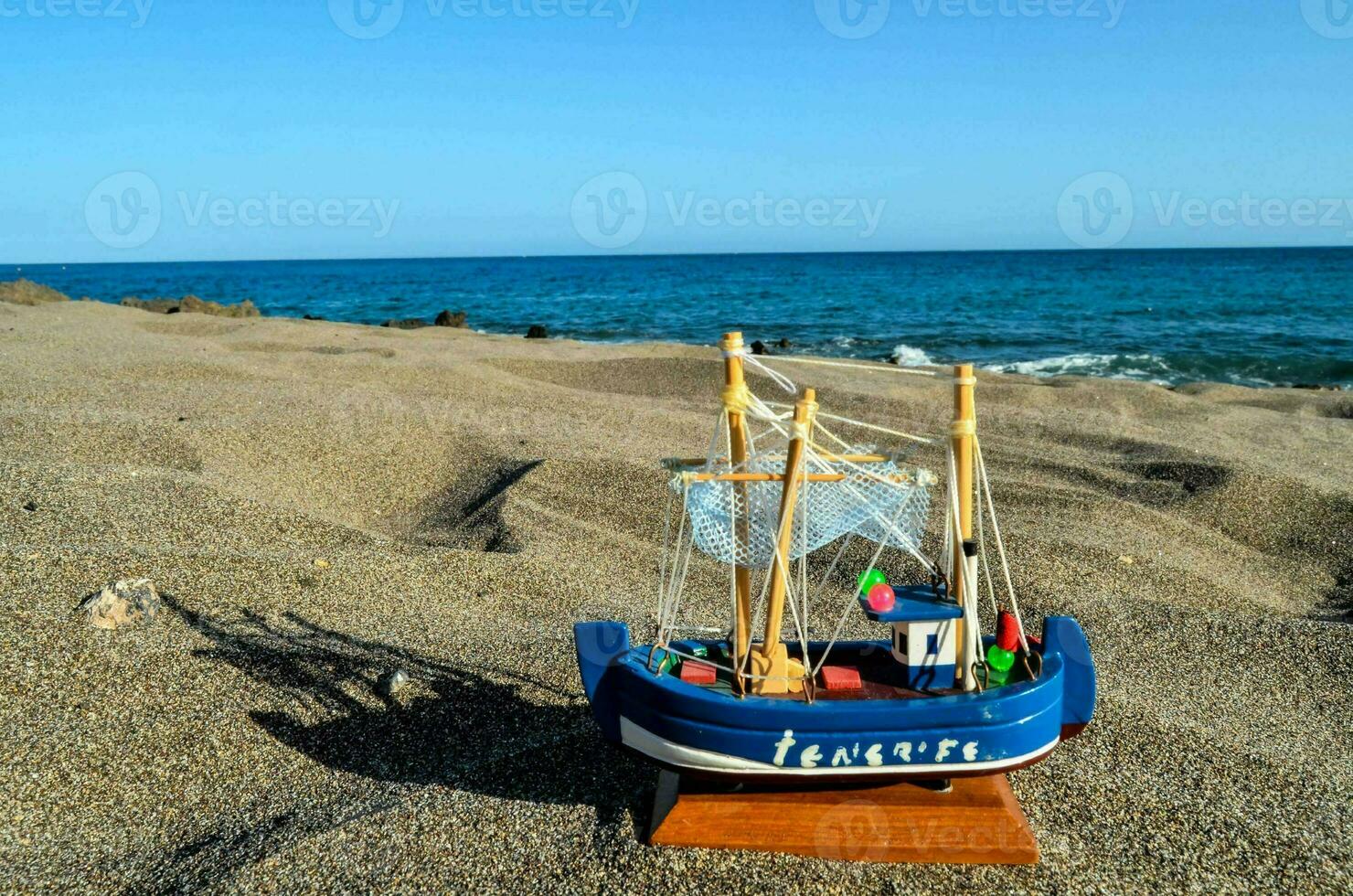 a toy boat on the beach with the ocean in the background photo