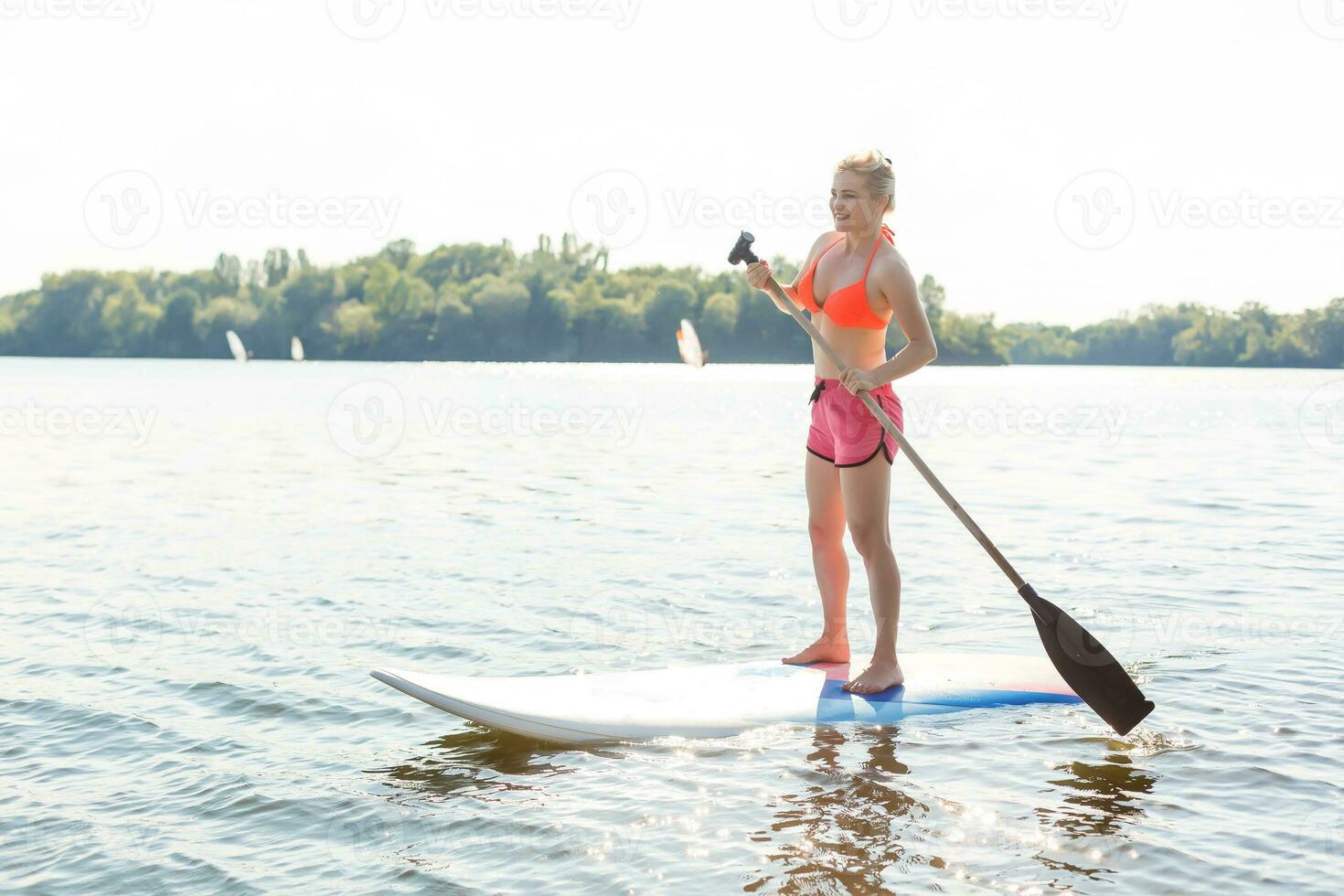 Young attractive woman on stand up paddle board in the lake, SUP photo