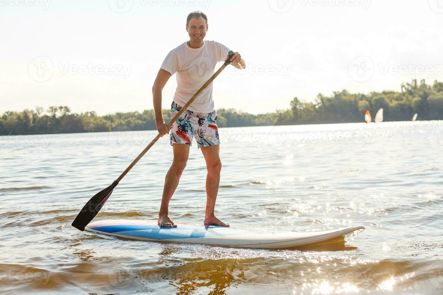 Silhouette of stand up paddle boarder paddling at sunset photo