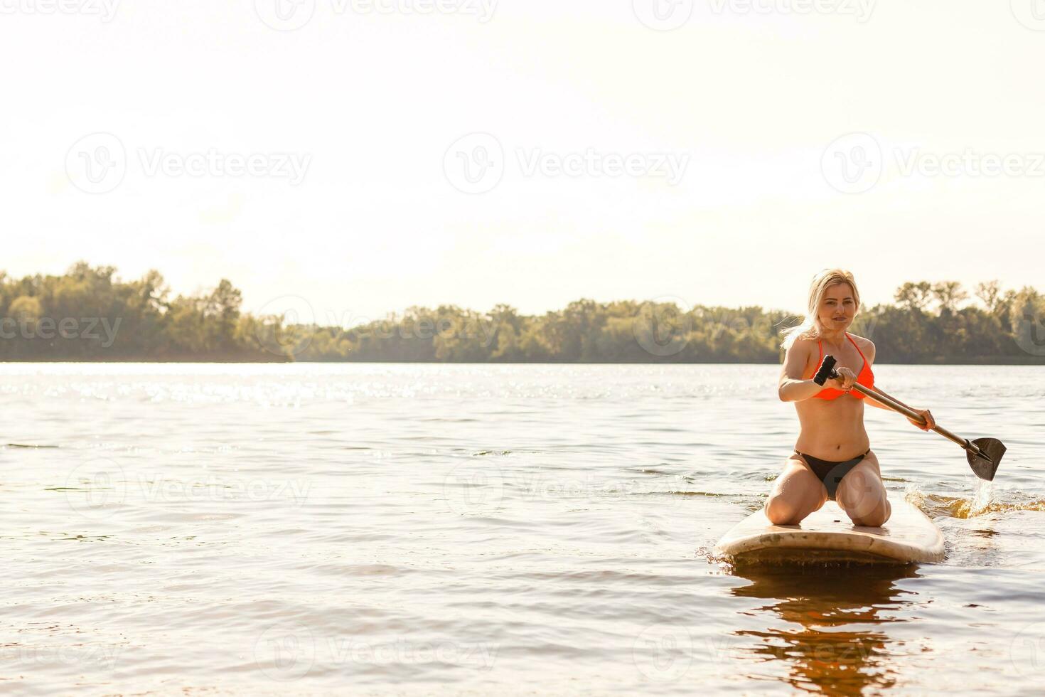 Young attractive woman on stand up paddle board in the lake, SUP photo