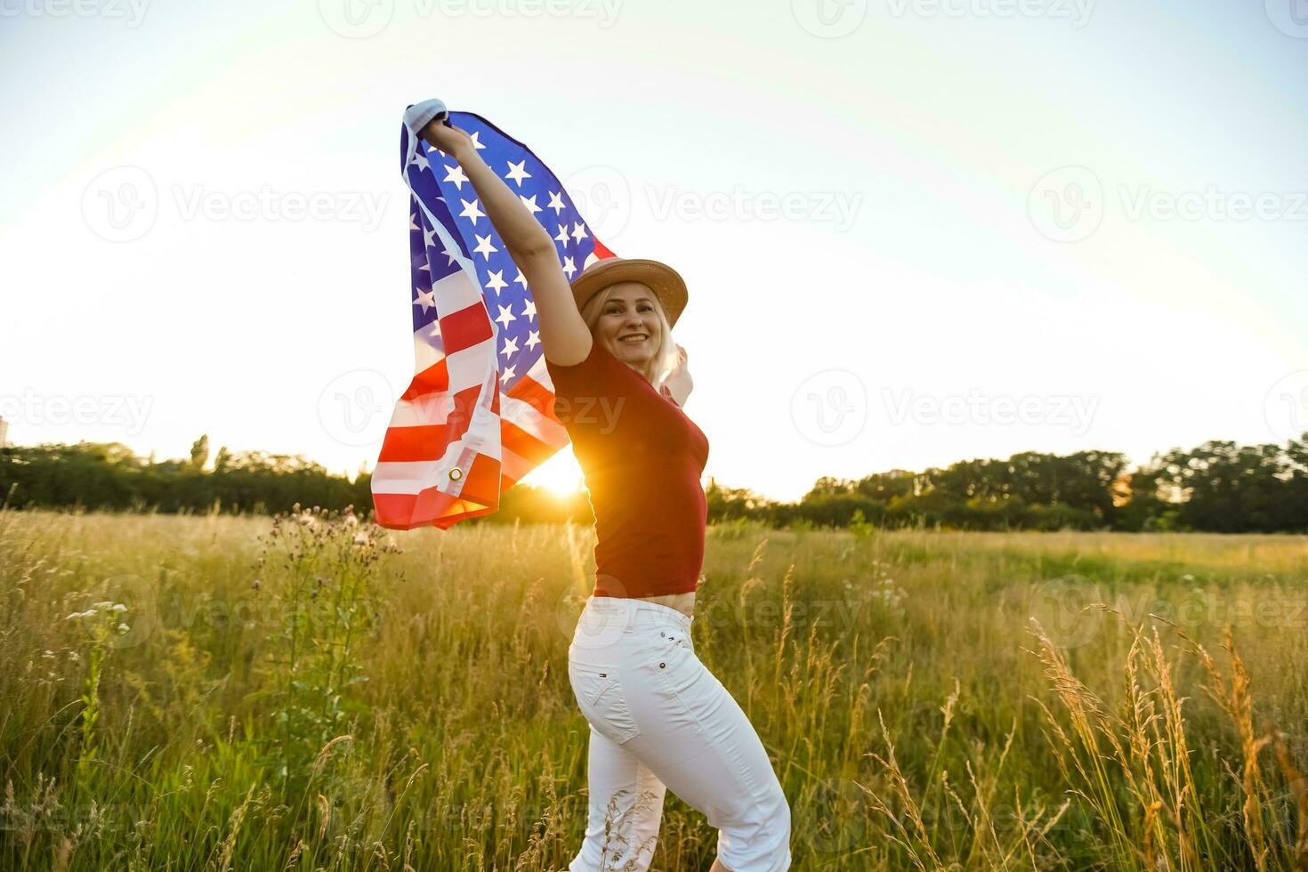 hermosa joven niña participación un americano bandera en el viento en un campo de centeno. verano paisaje en contra el azul cielo. horizontal orientación. foto