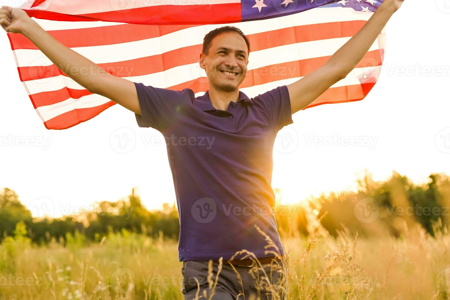 Fourth of July. Patriotic man with the national American flag in the field. Young man proudly waving an American flag. Independence Day. photo