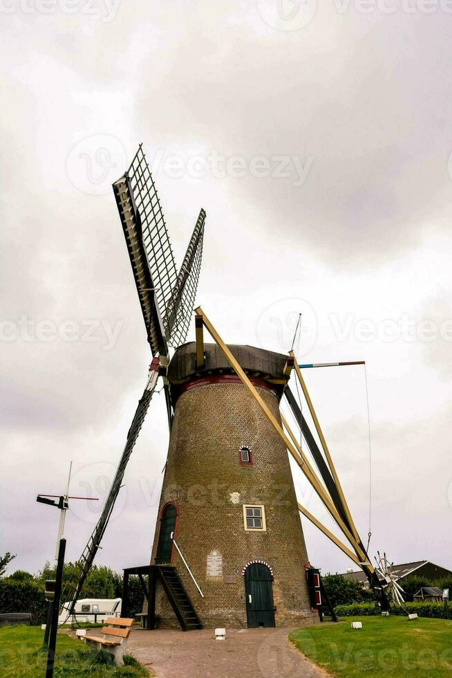 un molino en un herboso campo con un nublado cielo foto