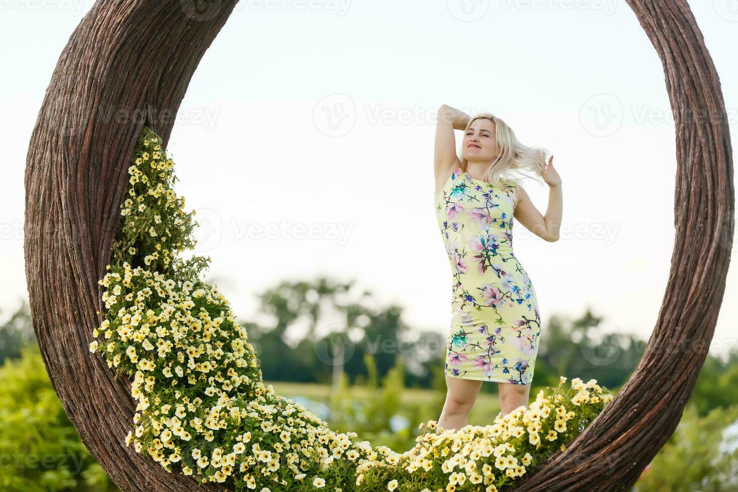 Beautiful young woman in nice dress posing on colorful wall of flowers. Fashion photo, nice hair, big smile photo