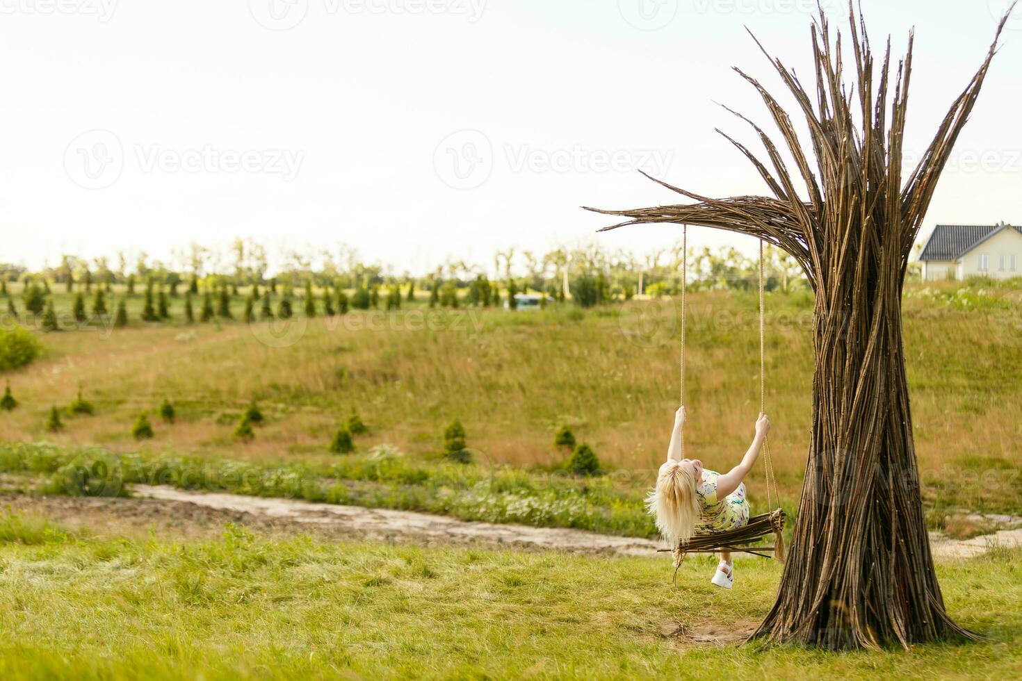 A young woman is swinging on a swing in a park setting. photo