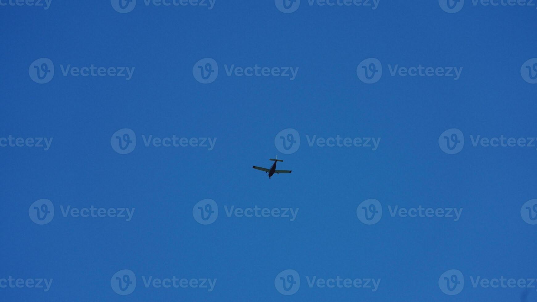 An airplane flying through the clear blue sky in the sunny day photo