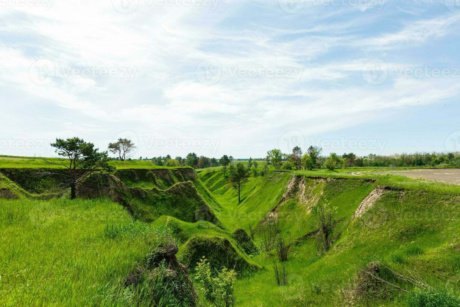 Spring photography, meadows, fields, ravines, hills, rural landscape. A deep, narrow gorge with steep slopes. A naturally raised area of land, not as high or craggy as a mountain. photo