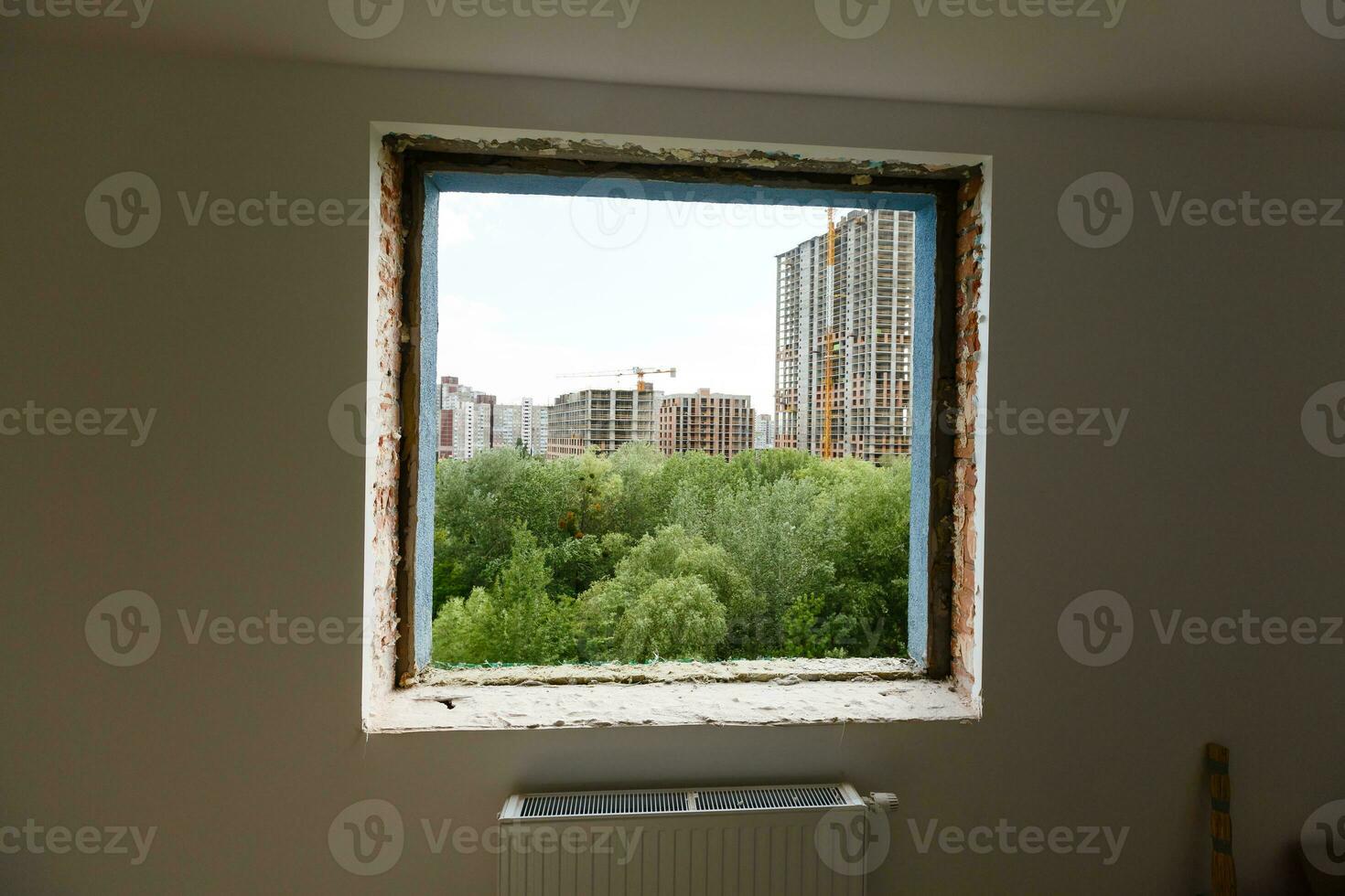 Empty frame on a wide panoramic window. Gorgeous view from the window of an apartment in a multi-storey building. Roofs of houses and trees from a height. Beautiful view through the window. Frame for photo