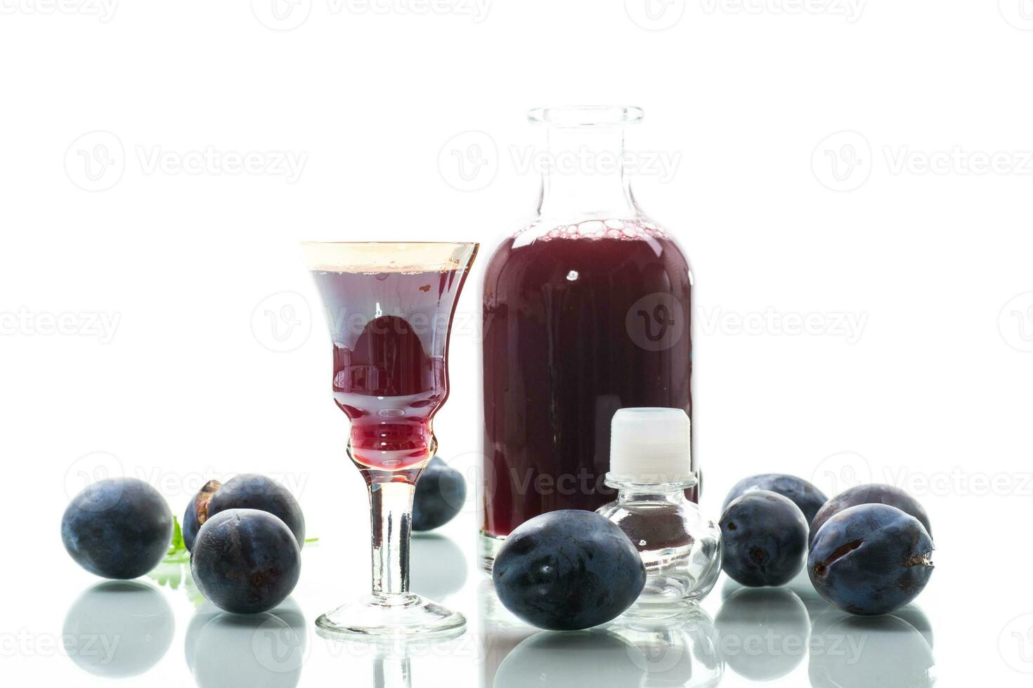 plum red wine in a glass and a decanter against the background of ripe large plums photo