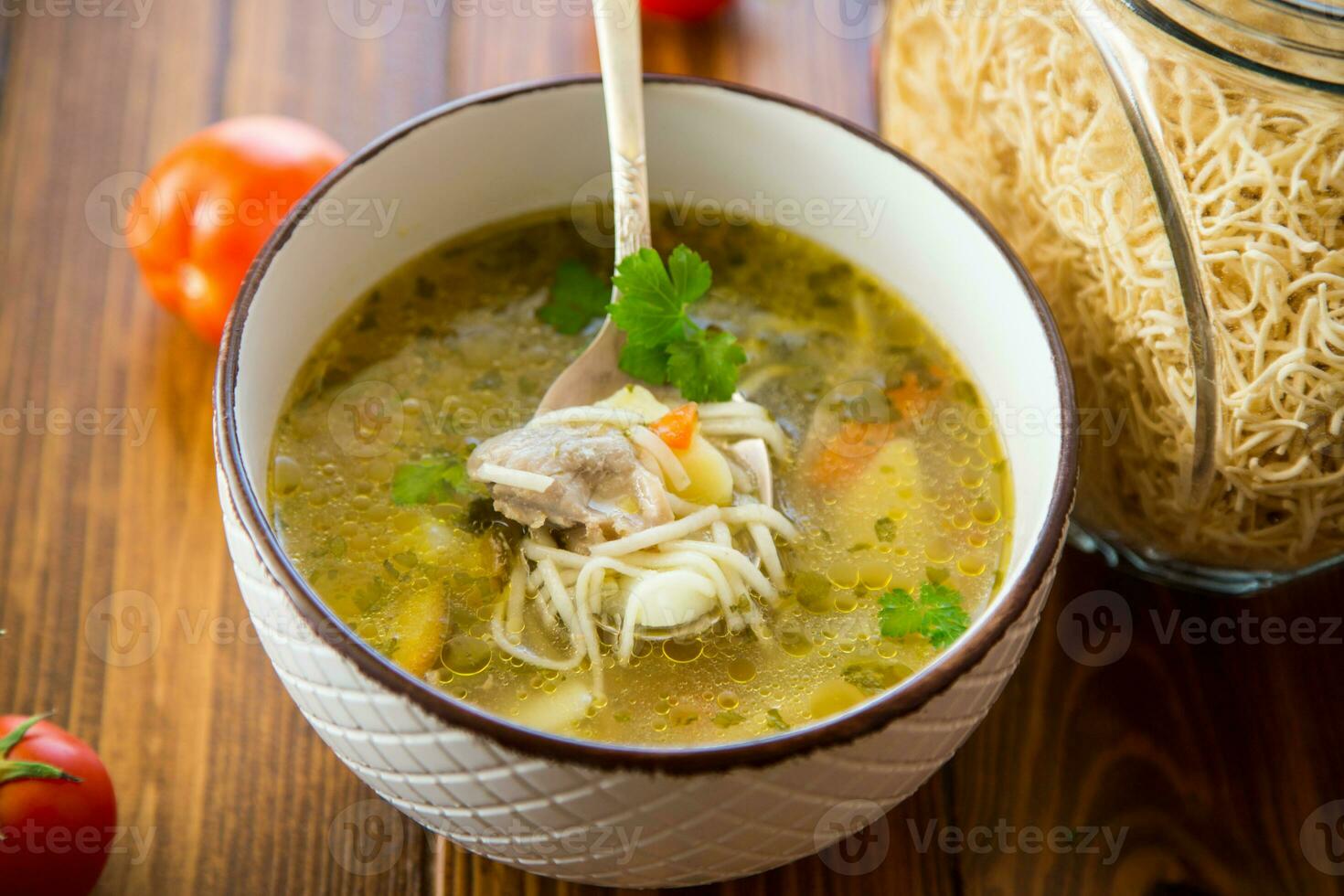 Chicken noodle soup with parsley and vegetables in a white plate photo