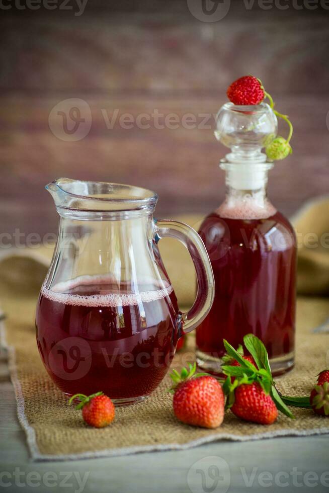 sweet cooked strawberry syrup in a glass decanter photo