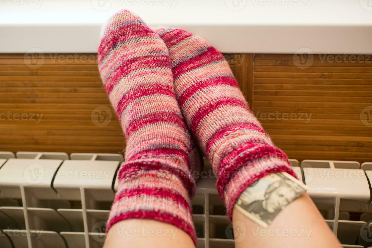 Feet in warm winter socks warm up on the radiator. photo