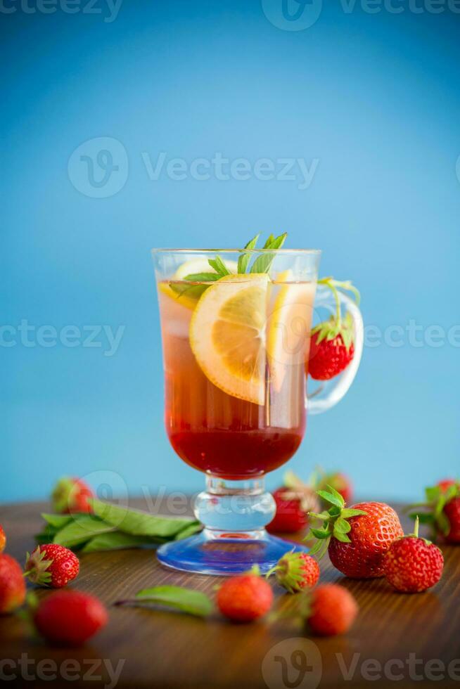 refreshing cool strawberry lemonade with lemon, ice and mint in a glass photo