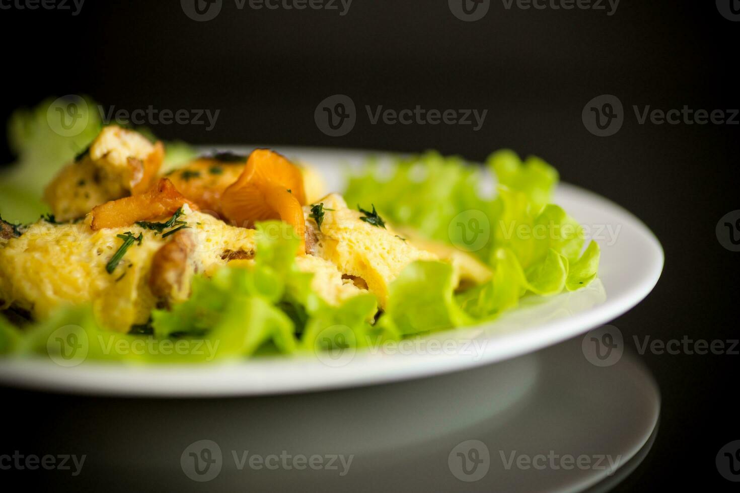 fried omelet with forest mushrooms chanterelles, on black background photo