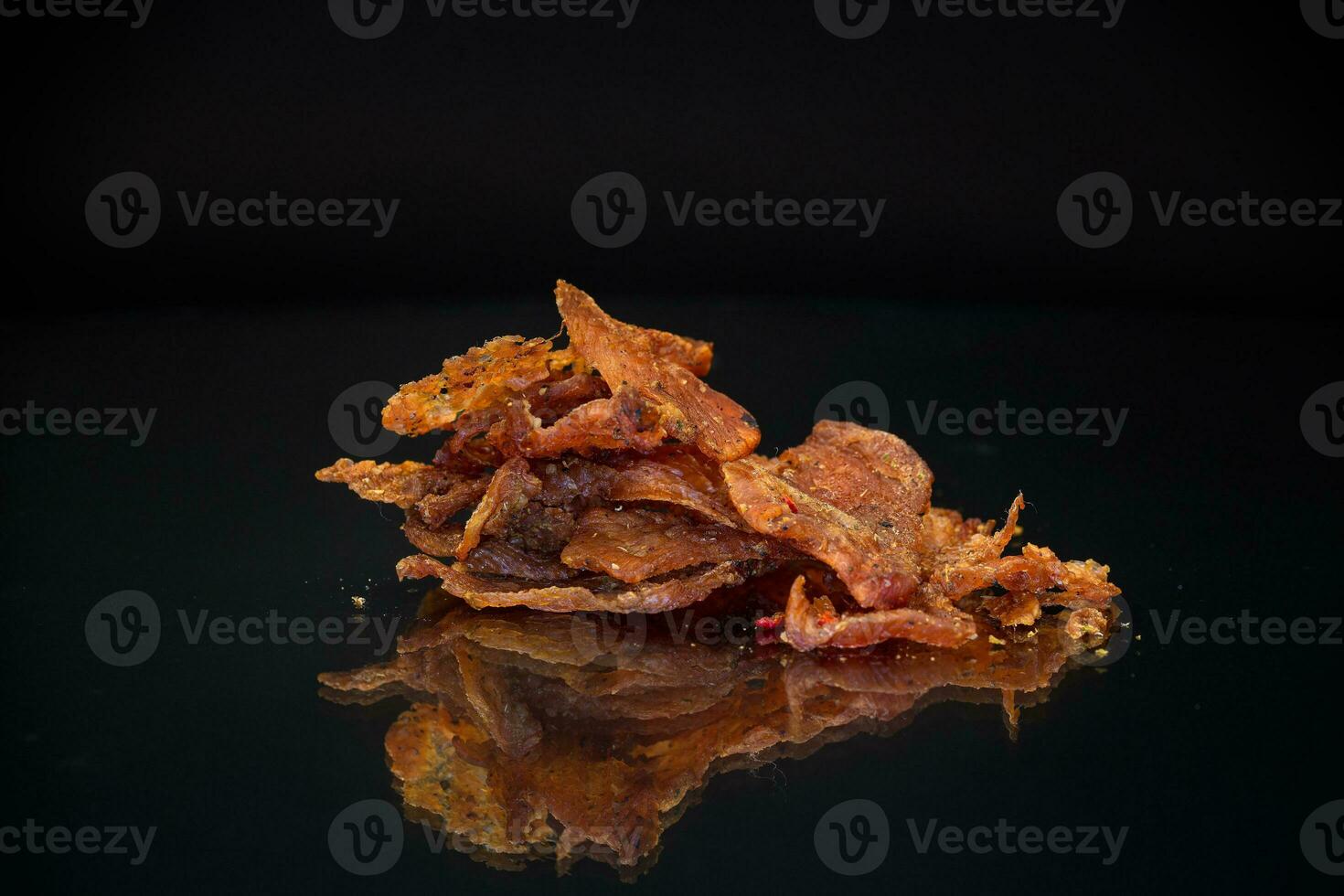 handful of dried meat marinated with spices, isolated on a black background. photo