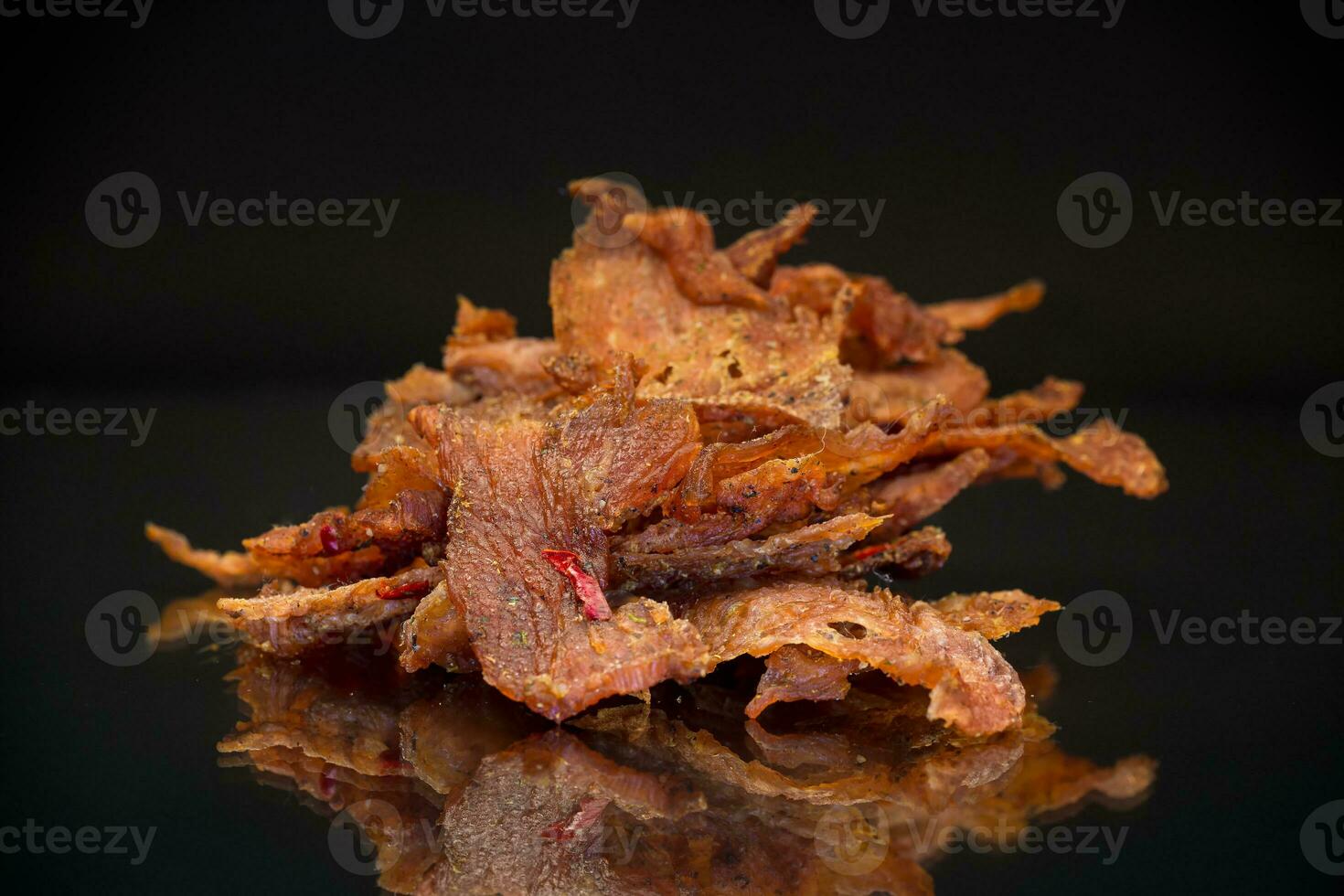 handful of dried meat marinated with spices, isolated on a black background. photo