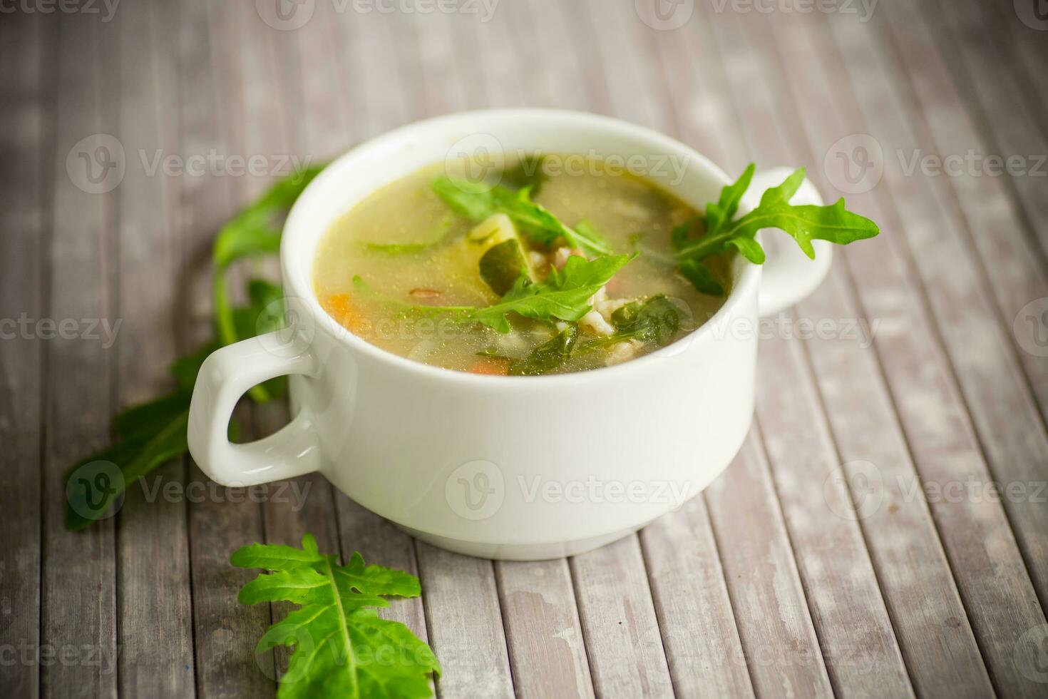 summer light soup with oatmeal and arugula in a plate photo