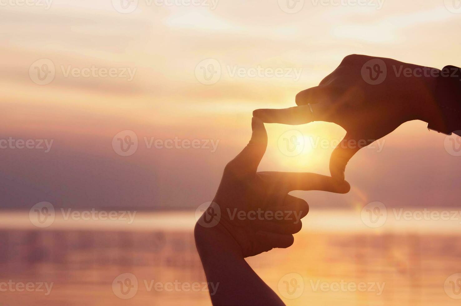 Finding inspiration and goals. A woman's hands create a frame and focus with the sunlight shining brightly in the morning. photo