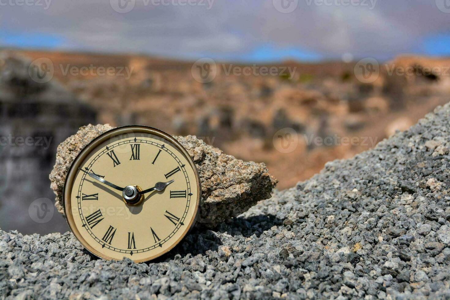 a small clock sits on top of a rock in the desert photo