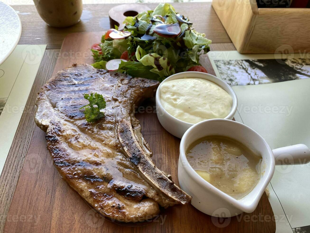 Grilled or fried pork chops on the bone with salad and mashed potatoes served on wooden board photo