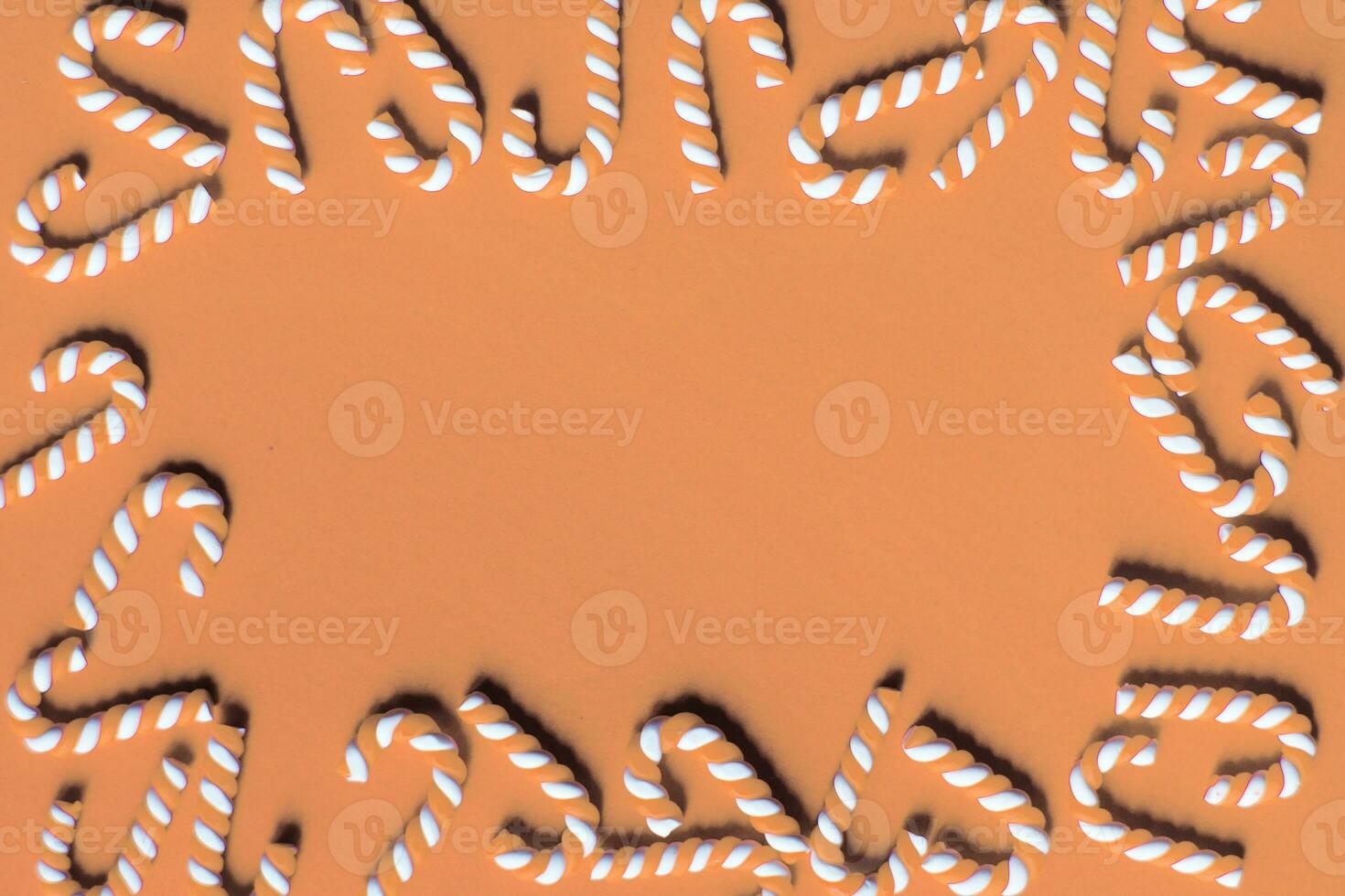Flat lay Christmas composition with frame of candy canes on a Peach Fuzz background. photo