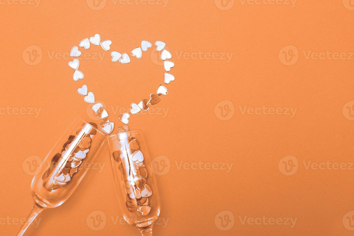 Glass of champagne with hearts on Peach Fuzz background. Valentines background, love, date concept photo