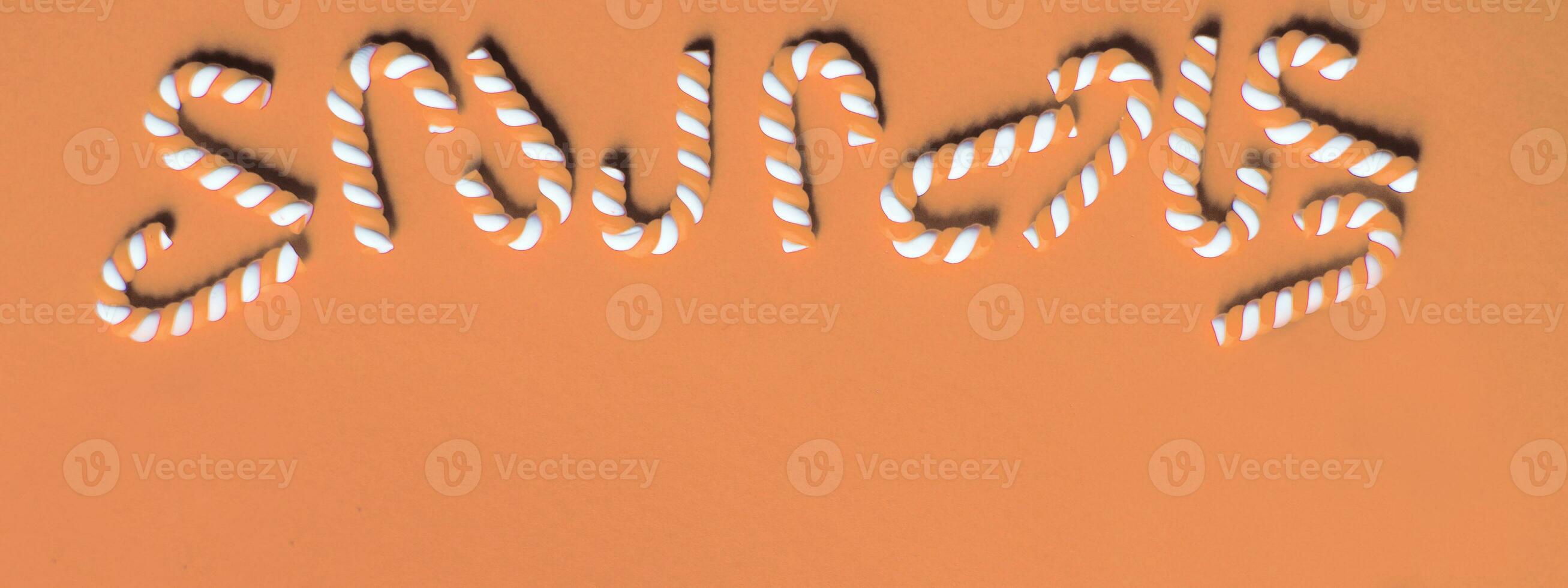 Flat lay Christmas composition with frame of candy canes on a Peach Fuzz background. photo