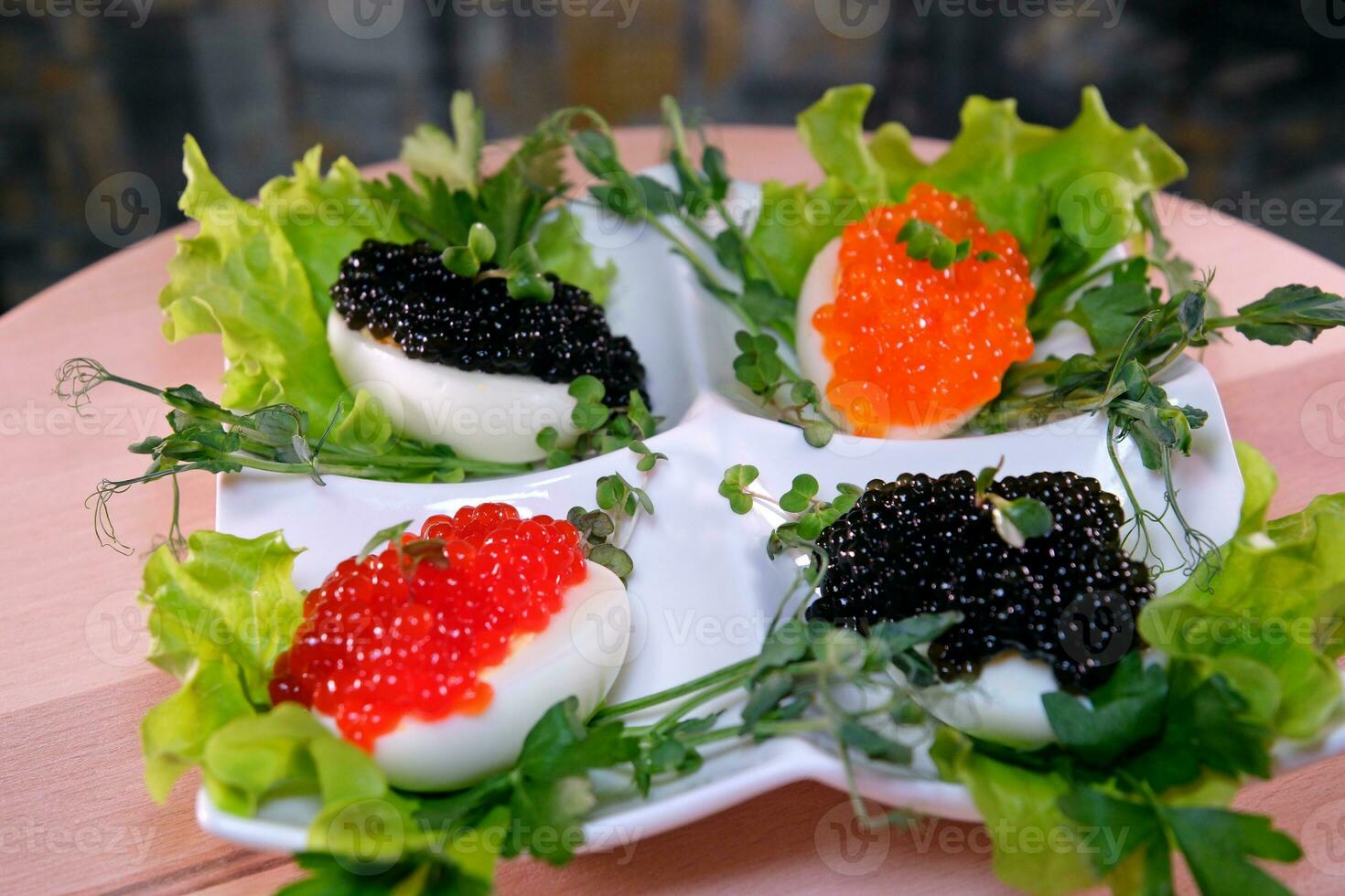 poner negro caviar en un huevo a servir delicioso sano comida mitades de un hervido pollo huevo con rojo caviar en un de madera antecedentes. foto