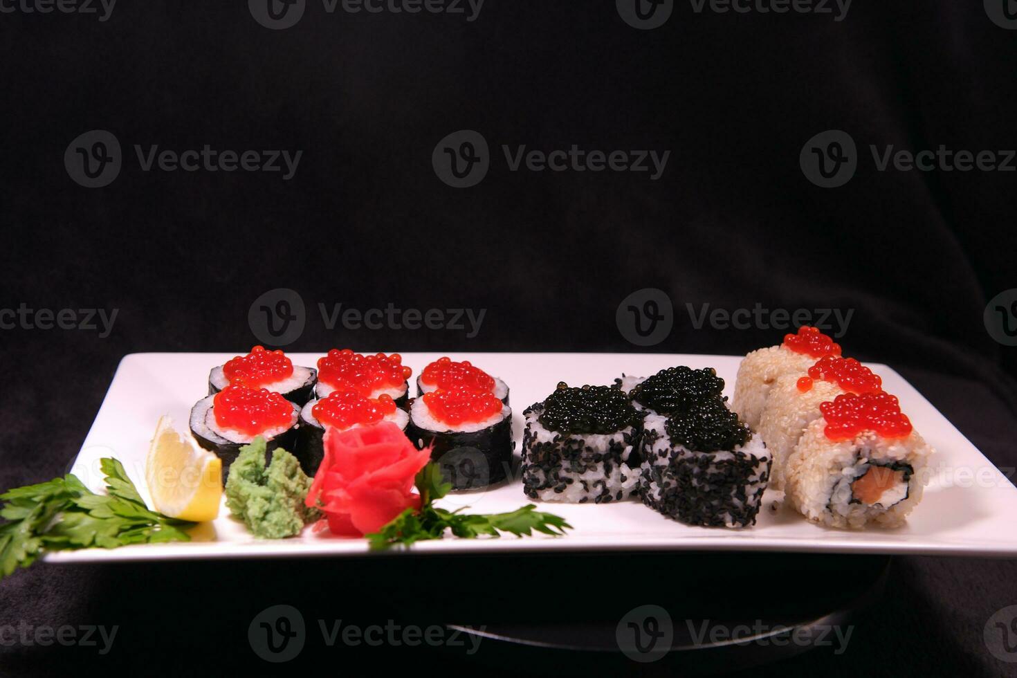 Three types of sushi rolls with white and black sesame seeds with black paddlefish caviar, red chum salmon caviar and pink salmon on one plate. Delicious food, beautiful presentation. photo