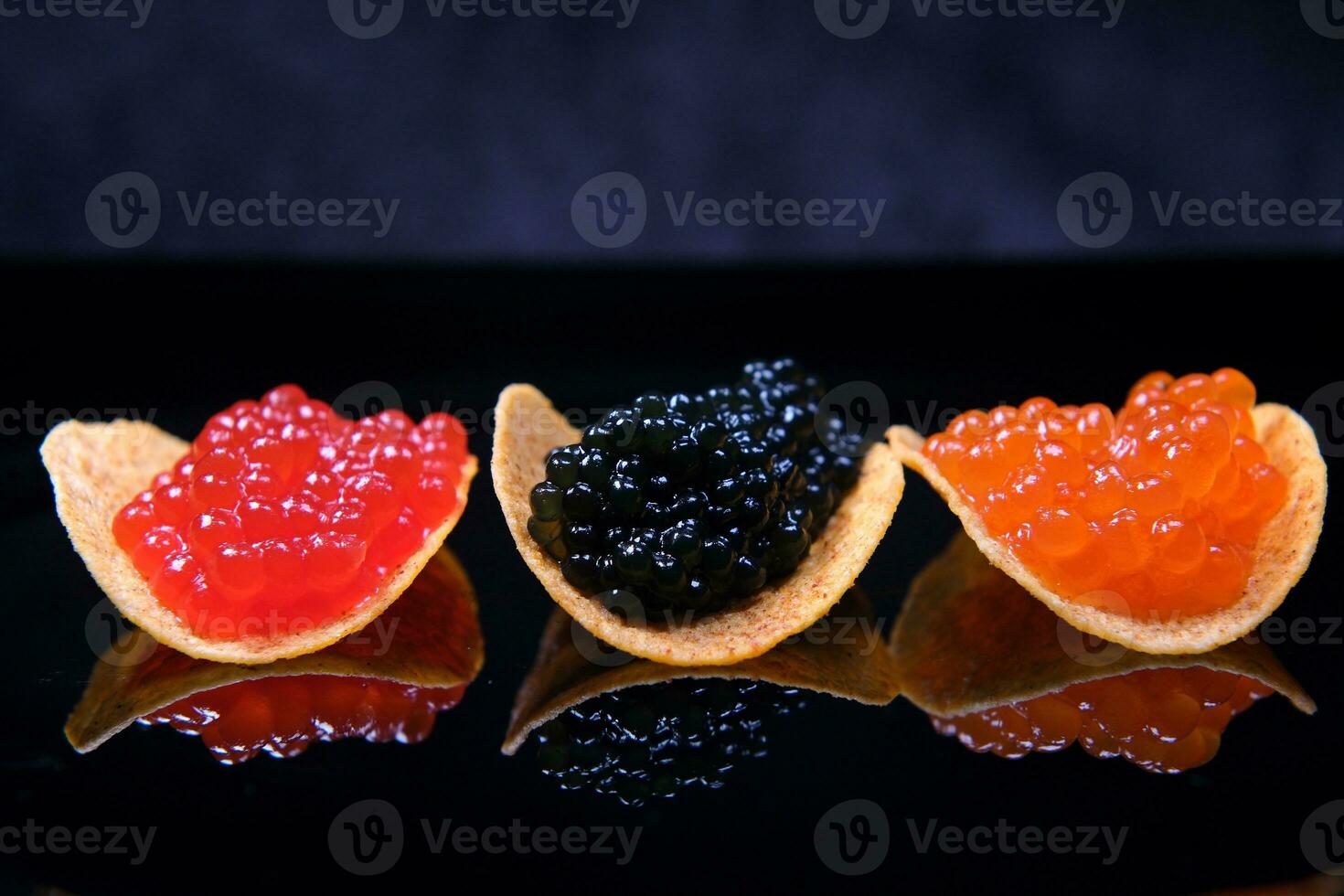 servicio pescado caviar rojo y negro caviar en papas fritas. oscuro antecedentes. caviar de rosado salmón, amigo salmón y pez espátula. sabroso hermosa saludable. salud beneficios de vitamina mi. hermosa mesa ajuste foto