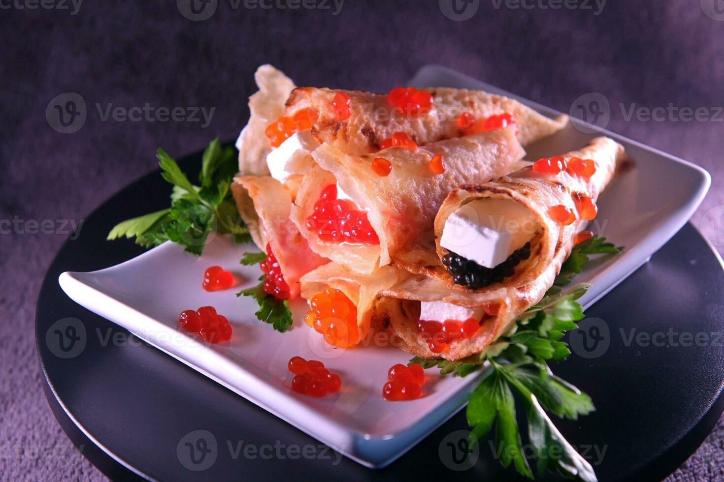 panqueques con rojo caviar , negro caviar con queso feta queso decorado con hierbas. delicioso sano comida foto