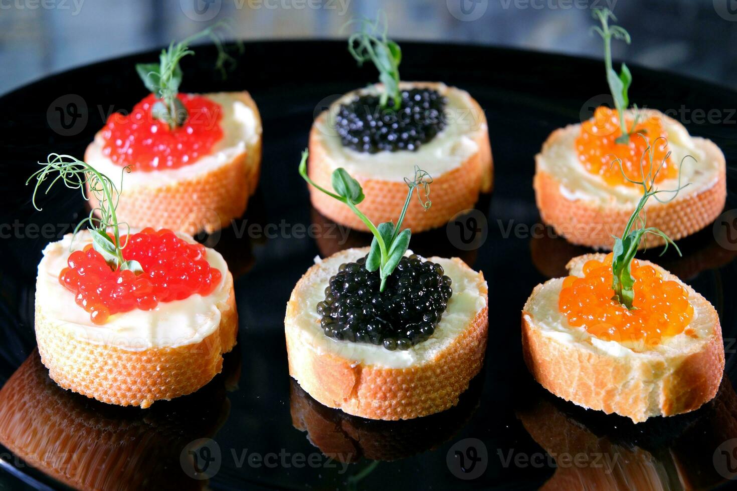 Partitioned dish with black and red caviar on wooden background photo