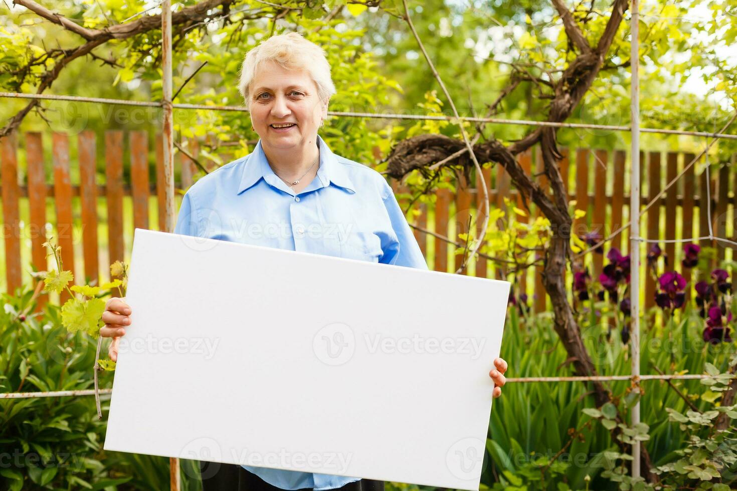 elderly woman holds a photo canvas
