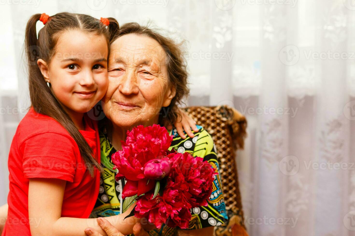 little girl giving her great grandmother a pink flower photo