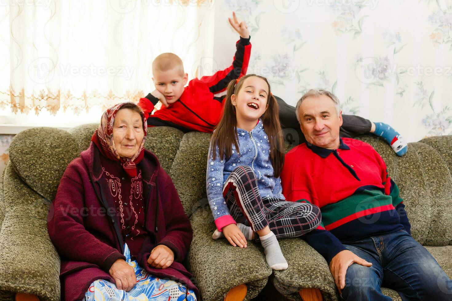 Grandchildren jumping on couch with their grandparents in the living room photo