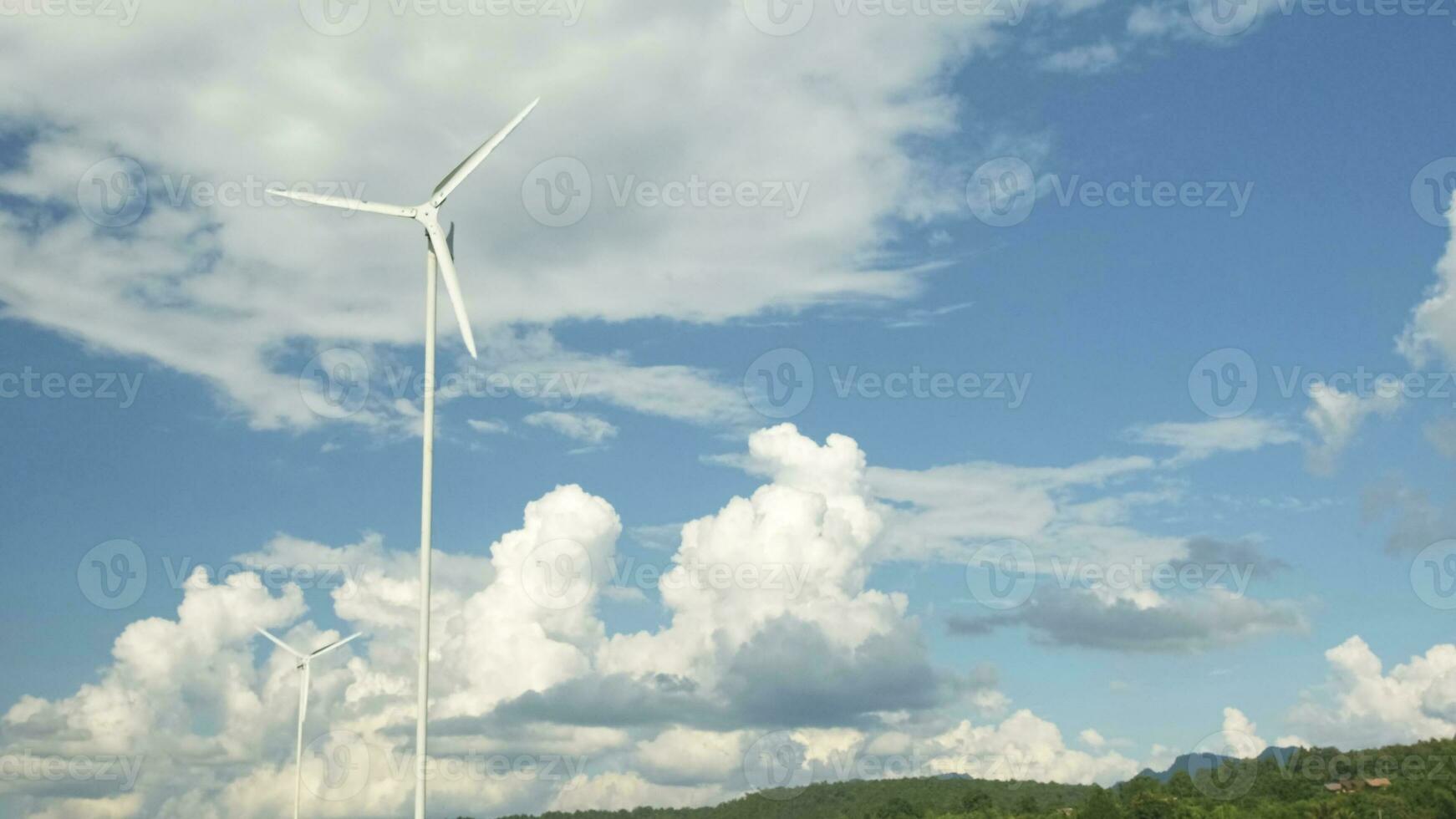 el blanco molinos de viento en azul cielo y nubes fondo, giro en viento a generar limpiar eléctrico energía industria, natural poder recurso tecnología para sostenible ecología y ambiente conservación. foto