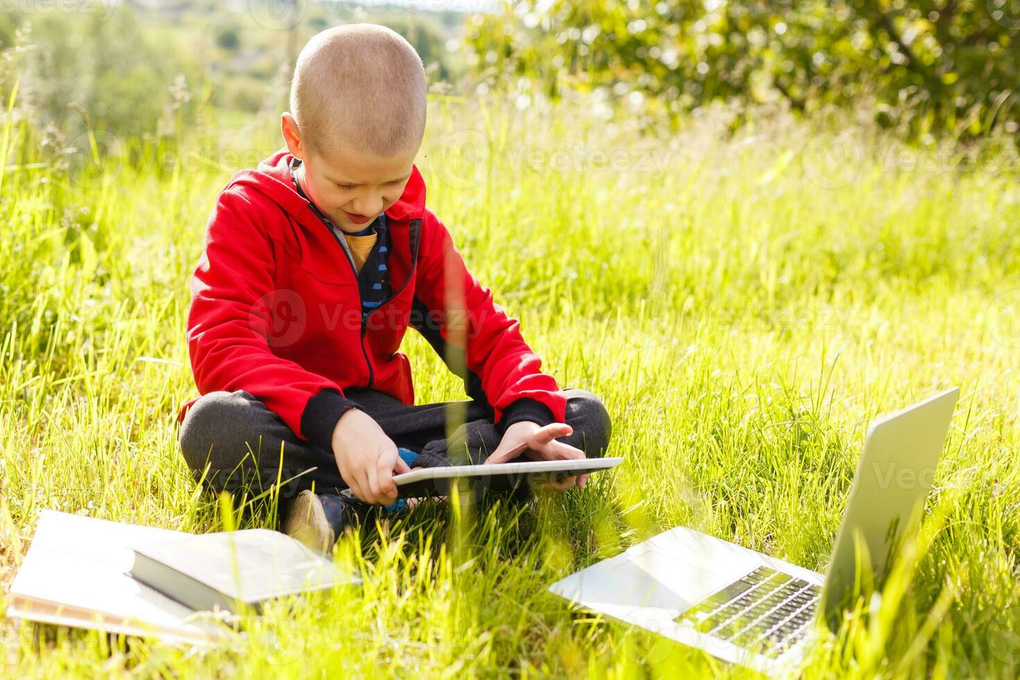 Distance learning. Boy learns autdoor laptop. Doing homework on grass. The child learns in the fresh air. The child's hands and computer photo