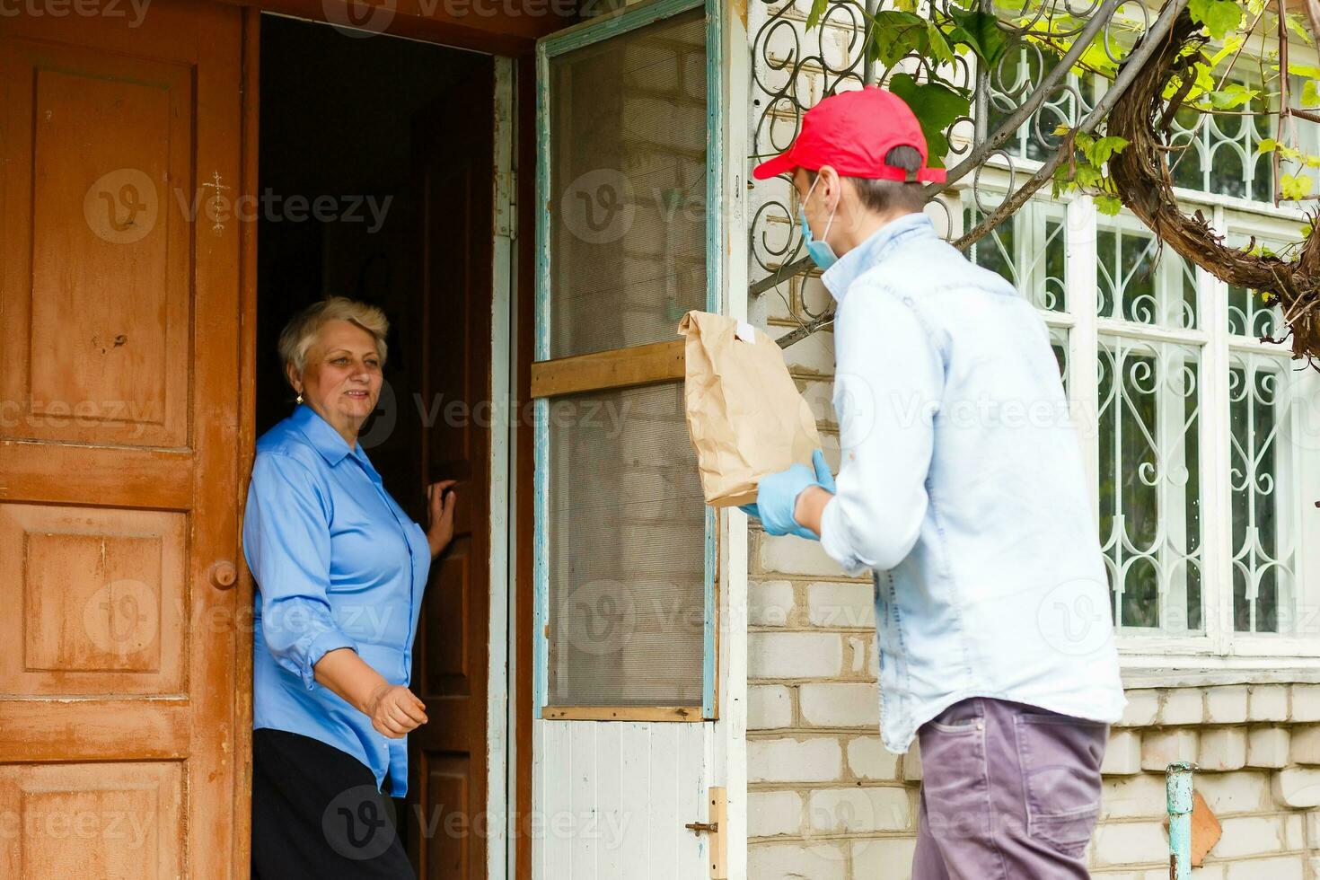 An elderly woman stays at home. Food delivery in a medical mask. photo